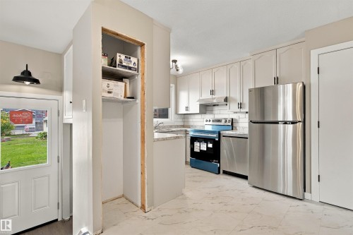 White cabinetry, stainless steel appliances, white subway tile backsplash, white countertops, and white flooring - 9908 99 Street, Morinville, AB 