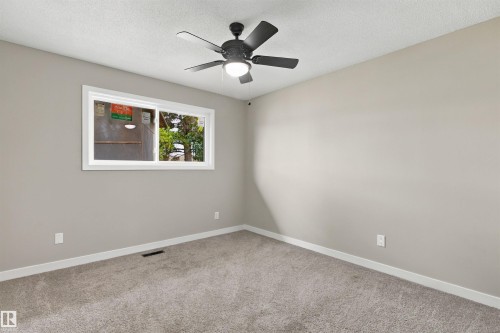 Light gray wall paint, gray carpet, matte black ceiling fan, white trim, and a built-in closet with a shelf - 9908 99 Street, Morinville, AB 