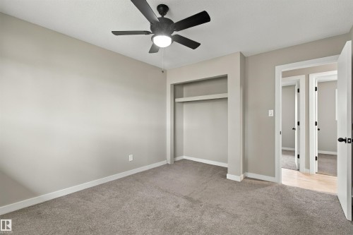 Neutral wall color, plush carpet, white window trim, and a ceiling fan with integrated lighting - 9908 99 Street, Morinville, AB 