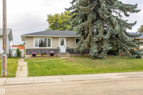 Siding exterior with stone accent, front entry with white door, and concrete front steps with handrail - 9908 99 Street, Morinville, AB 