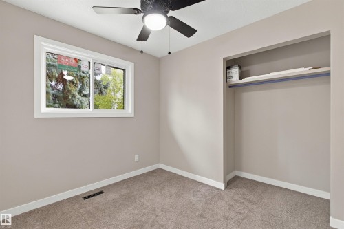 Neutral tone walls, grey carpet flooring, built-in closet shelving, ceiling fan, and white trim - 9908 99 Street, Morinville, AB 