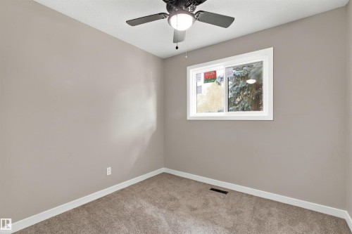 White paneled door with integrated window and matte black hardware, featuring a built-in upper cabinet and open lower storage space - 9908 99 Street, Morinville, AB 
