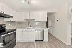 White cabinetry, stainless steel appliances, patterned tile backsplash, light-toned wood-finish flooring, and track lighting - 