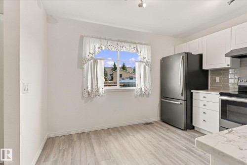 Wood-finish flooring, white cabinetry, stainless steel appliances, and a light-toned countertop - #3 18010 98 Av Nw, Edmonton, AB 