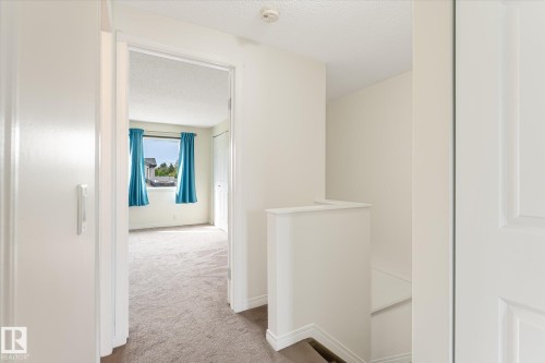 Hallway with carpeted flooring and stairway with white railing - #3 18010 98 Av Nw, Edmonton, AB 
