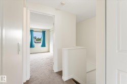 Hallway with carpeted flooring and stairway with white railing - 
