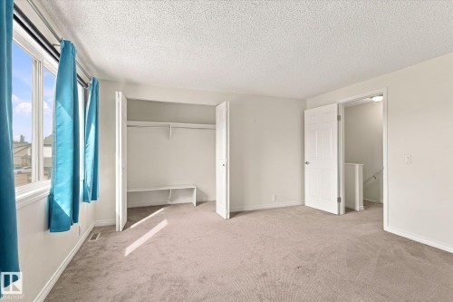 Expansive room with neutral carpeting, large windows, and an open closet featuring shelving - #3 18010 98 Av Nw, Edmonton, AB 