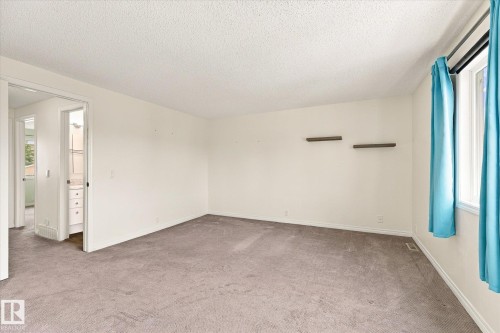 Carpeted room featuring white walls, a single window, and two floating wall shelves - #3 18010 98 Av Nw, Edmonton, AB 