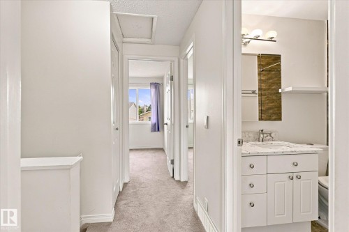 Hallway with neutral carpeting, white interior doors, and a built-in linen cabinet - #3 18010 98 Av Nw, Edmonton, AB 