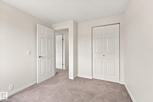 Neutral wall paint, textured ceiling, paneled interior doors, bi-fold closet doors, and light gray carpeting - #3 18010 98 Av Nw, Edmonton, AB 