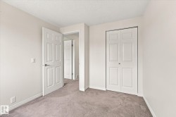 Neutral wall paint, textured ceiling, paneled interior doors, bi-fold closet doors, and light gray carpeting - 