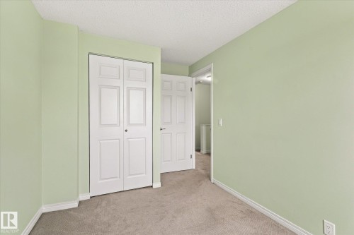 White bi-fold closet doors, secondary white paneled door, light green painted walls, and carpet flooring - #3 18010 98 Av Nw, Edmonton, AB 