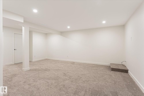 Expansive carpeted area with recessed lighting, white walls, and a white interior door - #3 18010 98 Av Nw, Edmonton, AB 