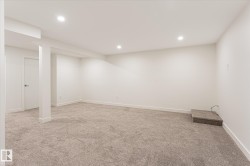 Expansive carpeted area with recessed lighting, white walls, and a white interior door - 