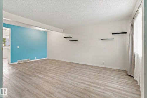 Wood-finish flooring, accent wall, built-in shelving, window with natural light, and ceiling texture - #3 18010 98 Av Nw, Edmonton, AB 