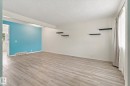 Wood-finish flooring, accent wall, built-in shelving, window with natural light, and ceiling texture - #3 18010 98 Av Nw, Edmonton, AB 