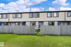 Rear exterior featuring light-colored siding, black-trimmed windows, and a private wooden fence - 