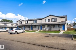 Townhouse exterior featuring light-colored siding, contrasting dark trim, and vibrant blue entry doors - 