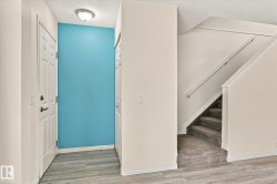 Foyer featuring wood-finish flooring, a paneled entry door, flush mount lighting, and a carpeted staircase with a handrail - 