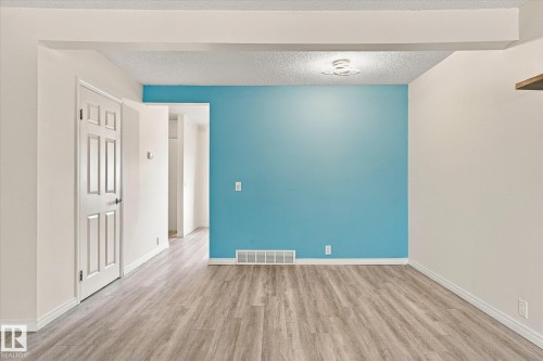 Wood-finish flooring, accent wall, overhead lighting, white trim, and a paneled door - #3 18010 98 Av Nw, Edmonton, AB 