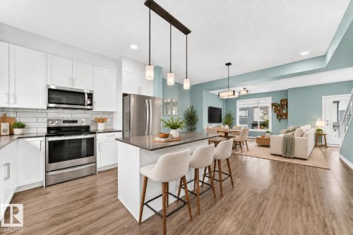 Kitchen featuring white shaker cabinetry, stainless steel appliances, and a central island with countertop seating - #56 804 Welsh Dr Sw, Edmonton, AB 