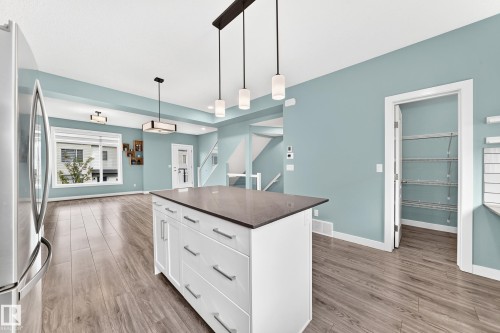 Central kitchen island with a dark countertop and white cabinetry - #56 804 Welsh Dr Sw, Edmonton, AB 