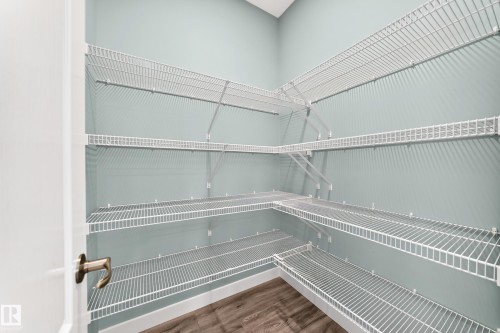Integrated wire shelving system with multiple tiers, light blue painted walls, and wood-finish flooring - #56 804 Welsh Dr Sw, Edmonton, AB 