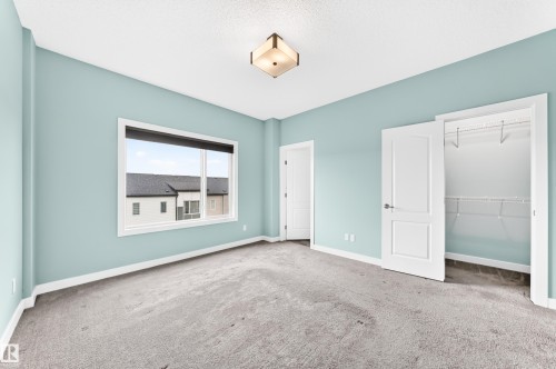 Light blue painted walls, grey carpeting, white trim, and a built-in closet with wire shelving - #56 804 Welsh Dr Sw, Edmonton, AB 