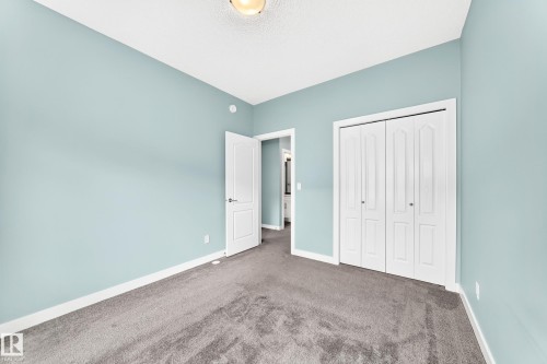 Textured carpeting, light blue wall paint, white trim, bifold closet doors, and a ceiling light fixture - #56 804 Welsh Dr Sw, Edmonton, AB 