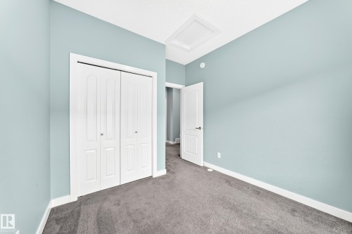 Plush carpet flooring, light blue wall paint, white interior doors, and a ceiling access panel - #56 804 Welsh Dr Sw, Edmonton, AB 