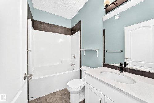 Bathroom featuring a white vanity with an integrated sink, matte black faucet, and a large wall-mounted mirror - #56 804 Welsh Dr Sw, Edmonton, AB 