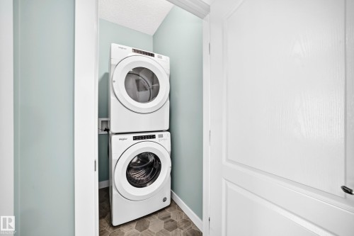 Stackable washer and dryer appliances, hexagonal floor tiling, and light blue wall finish - #56 804 Welsh Dr Sw, Edmonton, AB 