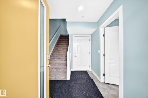 Staircase with carpeted treads and white handrail, paneled interior doors, and recessed lighting - #56 804 Welsh Dr Sw, Edmonton, AB 