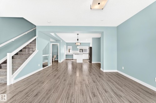 Wood-finish flooring throughout, with a carpeted staircase featuring a glass and white railing - #56 804 Welsh Dr Sw, Edmonton, AB 