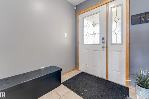 Entryway featuring a white door with decorative glass inserts, a coordinating sidelight, and wood trim - 4510 164A Ave Nw, Edmonton, AB 