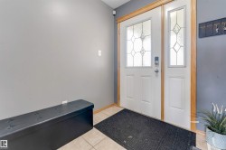 Entryway featuring a white door with decorative glass inserts, a coordinating sidelight, and wood trim - 