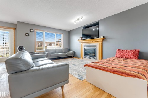 Hardwood flooring, large window with natural light, built-in fireplace with wood mantel, track lighting, and a neutral wall color - 4510 164A Ave Nw, Edmonton, AB 