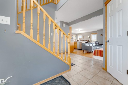 Light wood staircase with balusters, tile flooring, and a white paneled door with wood trim - 4510 164A Ave Nw, Edmonton, AB 
