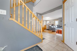 Light wood staircase with balusters, tile flooring, and a white paneled door with wood trim - 