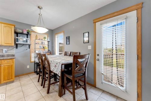 Tile flooring, wood cabinets, laminate countertops, built-in shelving, and a glass-paneled door - 4510 164A Ave Nw, Edmonton, AB 