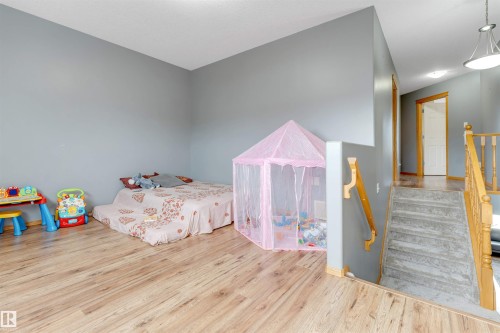 Wood-finish flooring, neutral wall paint, and natural wood railing - 4510 164A Ave Nw, Edmonton, AB 