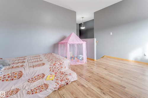 Wood-finish flooring with light-toned walls and trim, featuring a contemporary pendant light fixture - 4510 164A Ave Nw, Edmonton, AB 