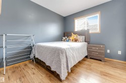 Wood-finish flooring with a neutral wall color, featuring a window with blinds and a ceiling-mounted light fixture - 