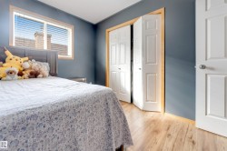 Wood-finish flooring, white paneled bifold closet doors, light wood trim, and a window with blinds - 