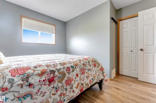 Light gray painted walls, wood-finish flooring, and a window with wood trim - 4510 164A Ave Nw, Edmonton, AB 
