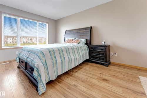 Wood-finish flooring, neutral wall tones, and a large window with horizontal blinds - 4510 164A Ave Nw, Edmonton, AB 