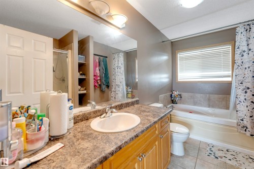 Bathroom featuring a spacious vanity with an integrated sink, built-in cabinetry, a shower-over-tub combination, and tiled flooring - 4510 164A Ave Nw, Edmonton, AB 