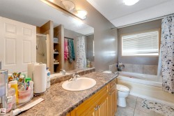 Bathroom featuring a spacious vanity with an integrated sink, built-in cabinetry, a shower-over-tub combination, and tiled flooring - 