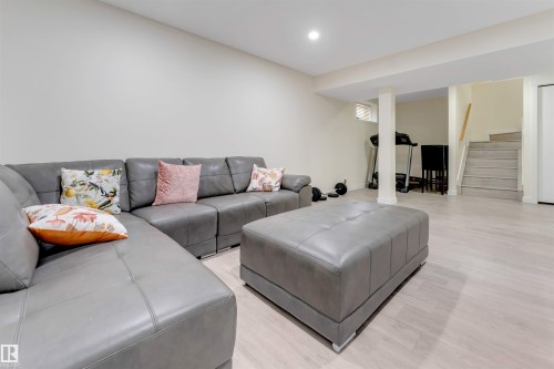 Recessed lighting illuminates the open-concept space featuring light wood-finish flooring and a staircase with a wood handrail - 4510 164A Ave Nw, Edmonton, AB 