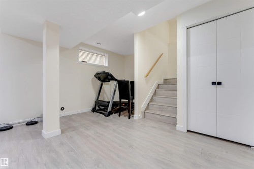 Light wood-finish flooring, white walls, built-in closet with modern hardware, and a window with blinds - 4510 164A Ave Nw, Edmonton, AB 